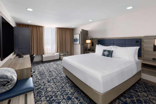 um quarto de hotel com uma cama grande e uma televisão em Wyndham DFW Airport em Irving