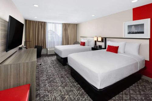 a hotel room with two beds and a flat screen tv at Ramada by Wyndham DFW Airport in Irving