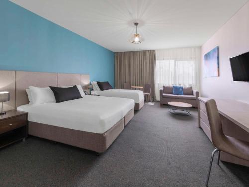 Habitación de hotel con 2 camas y sofá en Mantra Melbourne Melton en Melton