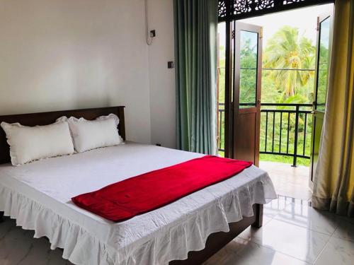 a bedroom with a bed with a red blanket on it at Sethumka Ayurveda & Yoga Resort in Wadduwa