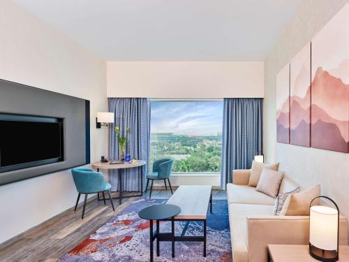 a living room with a couch and a tv at Novotel Mumbai International Airport in Mumbai