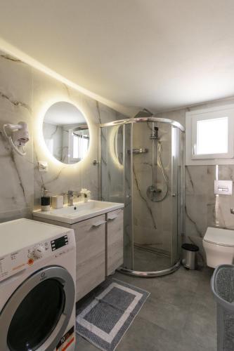 a bathroom with a shower and a washing machine at Balliu Apartment in Triovasálos