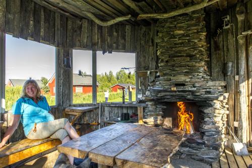 a woman sitting on a bench next to a stone fireplace at Ylläksen Yöpuu in Äkäslompolo