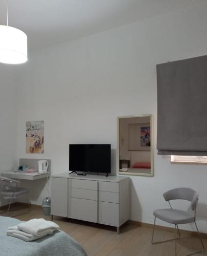 a living room with a tv and a desk with a chair at Suite Europa in San Vito dei Normanni