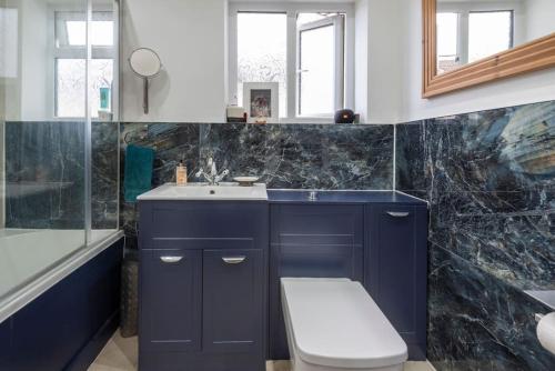 y baño con lavabo azul y aseo. en Stunning 3-Bed House, en Londres