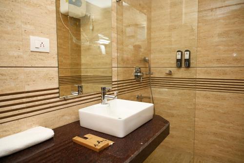 y baño con lavabo y ducha acristalada. en Hotel The Avoir Asansol, en Āsansol
