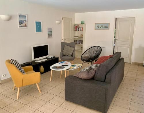uma sala de estar com um sofá e cadeiras e uma televisão em Villa piscine privée chauffée,vélos fournis, plage em Moliets-et-Maa