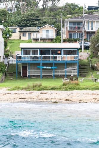a blue house on the beach next to the water at Beachfront Shack Malua Bay - Dog Friendly with EV Fast Chgr in Malua Bay