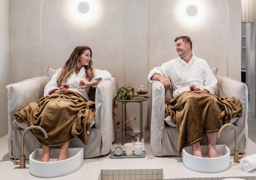 a man and woman sitting in chairs in a bath room at Hotel Olivewood in East London