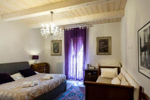una camera con due letti, un divano e un lampadario a braccio di Al Battistero Luxury Suite a Ravenna