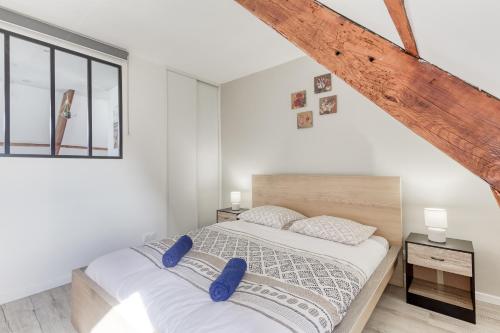 a white bedroom with a large bed with blue pillows at Le Boisier - 3 min de la Gare Massy TGV - Cozy Houses in Palaiseau