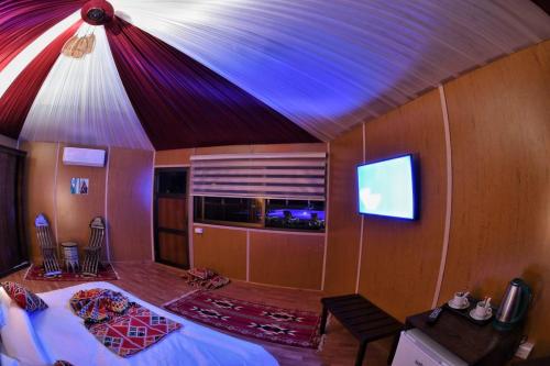 a bedroom with a bed and a tv on the wall at Rum Oasis Luxury Camp in Wadi Rum