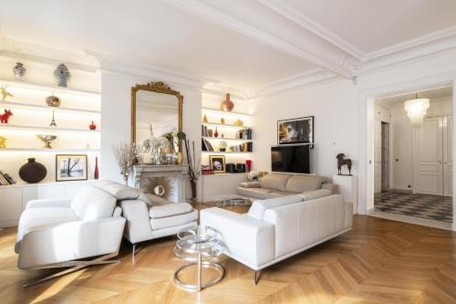 Elle comprend un salon doté d'un mobilier blanc et d'un miroir. dans l'établissement Deluxe Paris St Germain Suite, à Paris