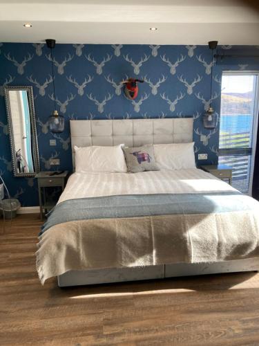1 dormitorio con 1 cama grande y pared azul en Skyefall Self Catering, en Uig
