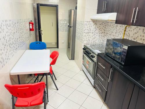 una cocina con mesa y sillas rojas. en Private Room in beautiful Appartment, en Dubái