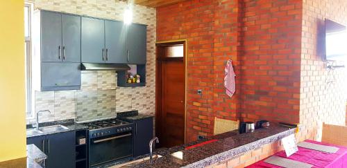 uma cozinha com armários azuis e uma parede de tijolos em Kivu Summer Hotel em Rubavu