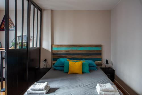 une chambre avec un lit avec des oreillers bleus et jaunes dans l'établissement Studio calme et accueillant Metro Charonne, à Paris