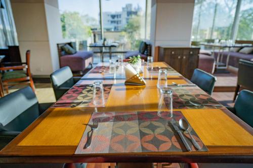 a long wooden table in a restaurant with chairs at Royal Orchid Central Jaipur, Bani Park in Jaipur