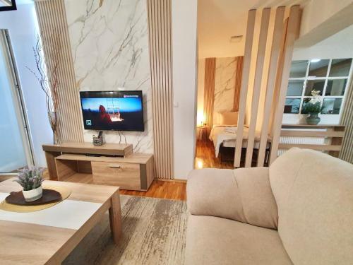 a living room with a couch and a television at Lux Apartment Dolce Casa Skopje Karpos IV in Dolno Nerezi