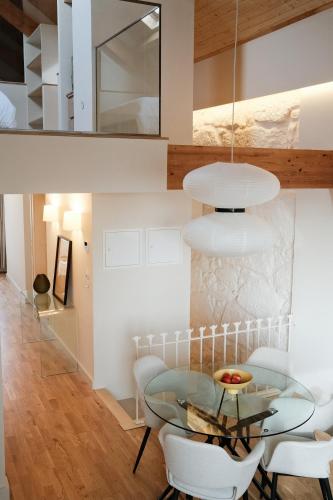 a dining room with a glass table and white chairs at Corujeira Apartments by MyALPlace in Porto