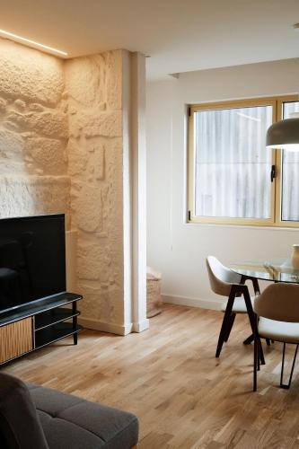 a living room with a tv and a dining room table at Corujeira Apartments by MyALPlace in Porto
