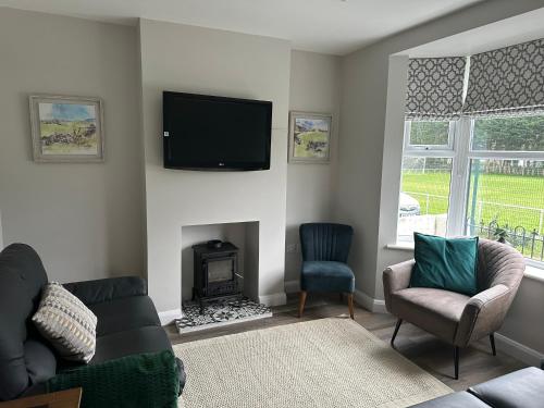 sala de estar con chimenea y TV en la pared en Homely house at the foot of Snowdonia, en Llanberis