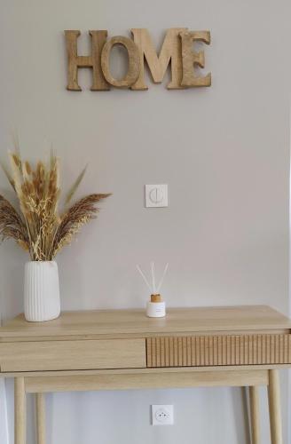 un panneau d'identification en bois sur une table avec deux plantes dans l'établissement Comme à la 