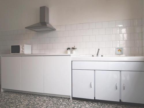 een keuken met witte kasten en een wastafel bij appartamenti olivo in Vigevano