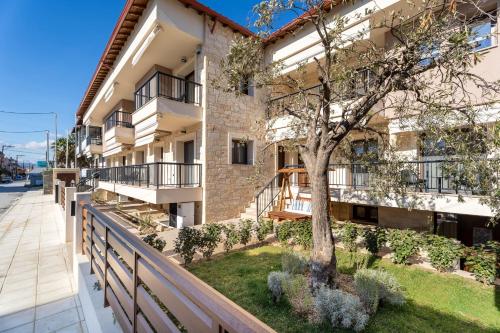 an apartment building with a tree on a balcony at Mpikas Holidays in Ierissos