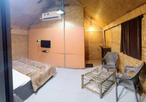 マハバレシュワールにあるForest Villas And Tentsのベッドと椅子が備わる客室です。