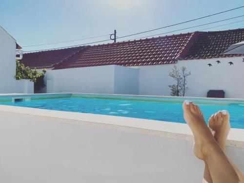 a person sitting on the edge of a swimming pool at Casas do Patheo in Óbidos