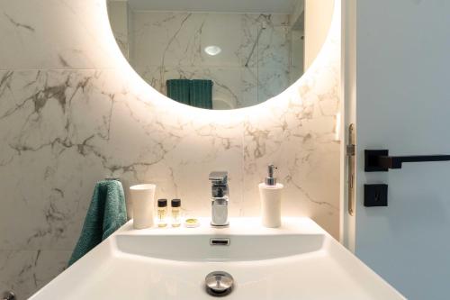 a bathroom with a white sink and a mirror at Arcade Apartments in Volos