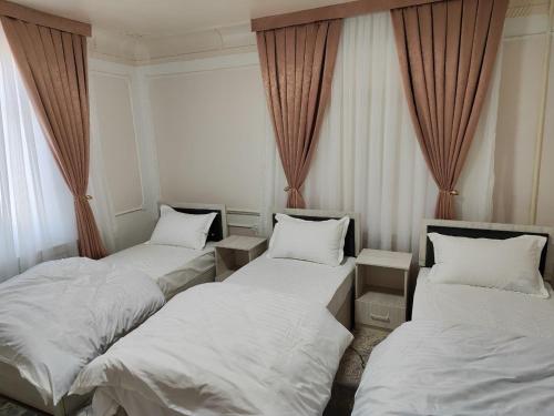 three beds in a room with curtains at MiCasa Family Guesthouse in Tashkent