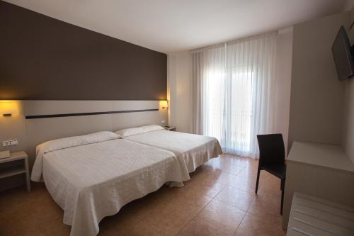 um quarto com uma cama branca e uma janela em Hotel Costa Brava em Blanes