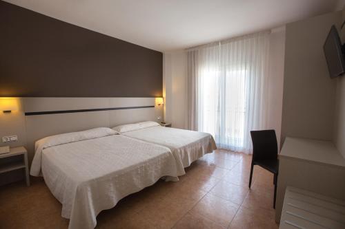a bedroom with a white bed and a window at Hotel Costa Brava in Blanes