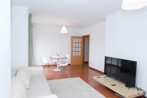 a living room with a white couch and a tv at Paulo Guest Apartment by Rosado in Caldas da Rainha