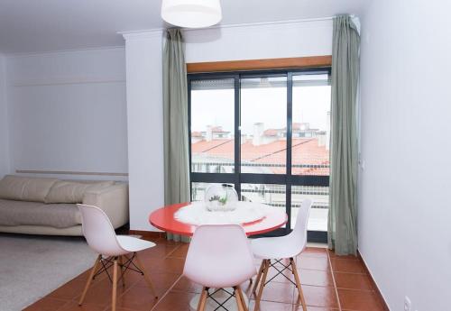 um quarto com uma mesa e cadeiras e uma grande janela em Paulo Guest Apartment nas Caldas da Rainha