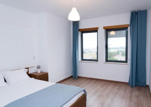 um quarto com uma cama e duas janelas em Paulo Guest Apartment nas Caldas da Rainha