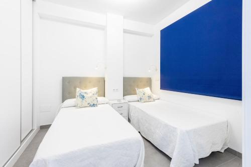 two beds in a room with a blue wall at Edificio Sirena in Nerja