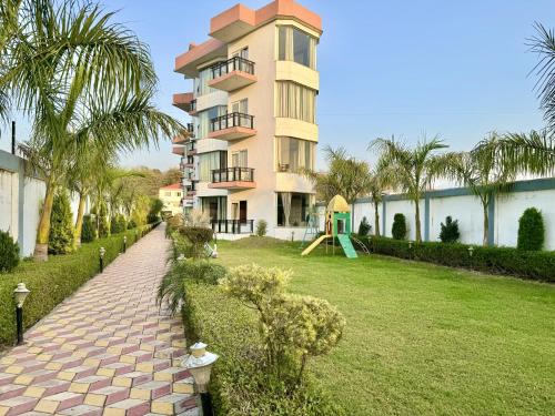 a large building with a playground in front of a yard at Sumedha Resort & SPA Rishikesh in Rishīkesh
