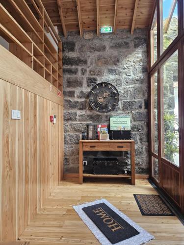 a room with a stone wall with a clock on the wall at Casa do Cinzeiro in Nordeste