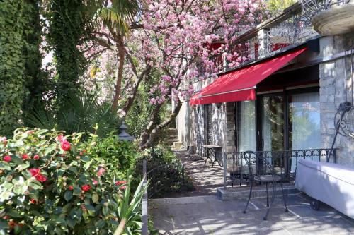 a patio with a red awning and pink flowers at Barony Le Pergole holiday apartments Lugano in Lugano