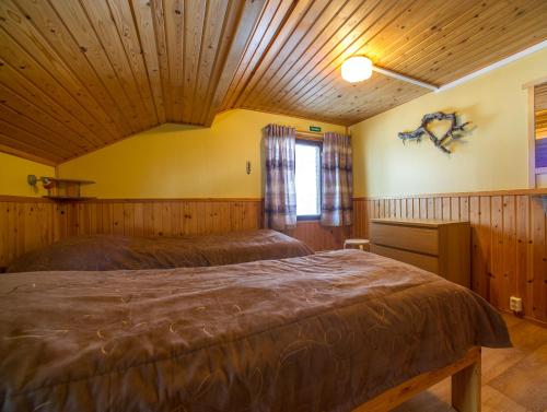 a bedroom with two beds in a room with wooden walls at Ylläksen Yöpuu in Äkäslompolo