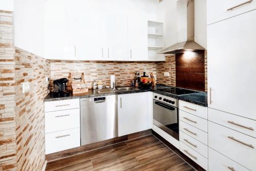 a kitchen with white cabinets and a brick wall at BackHome - Fantastische Schlosslage, SmartTV, Netflix, 50qm, 24h Checkin - Apartment 1 in Ludwigsburg