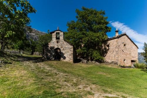 an old stone church in a field with a tree at Casas Rurales Molinias in Fosado