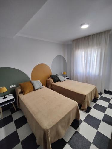 two beds in a room with a checkered floor at Casa Baire in Puigmoreno