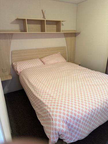 a bedroom with a bed with a checkered blanket at 3 BEDROOM CARAVAN AT THE GRANGE HOLIDAY PARK, CHAPEL ROAD INGOLDMELLS in Addlethorpe