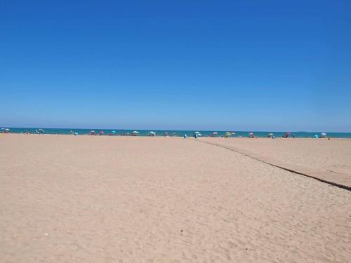 a sandy beach with umbrellas and the ocean at ApartUP Patacona Infinity in Valencia