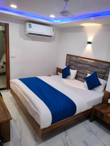 Hotel Angell Park في أحمد آباد: غرفة نوم بسرير كبير مع وسائد زرقاء