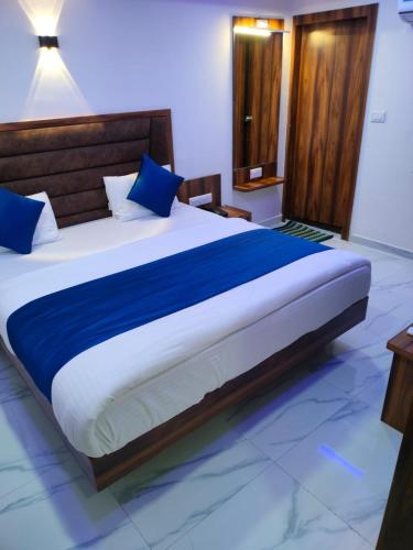 a bedroom with a large bed with blue pillows at Hotel Angell Park in Ahmedabad